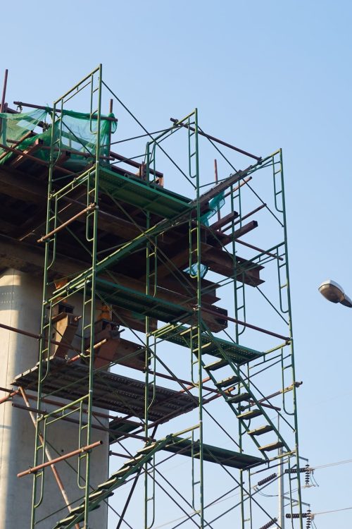 Construction of a high-rise building with scaffolding and construction equipment on blue sky background